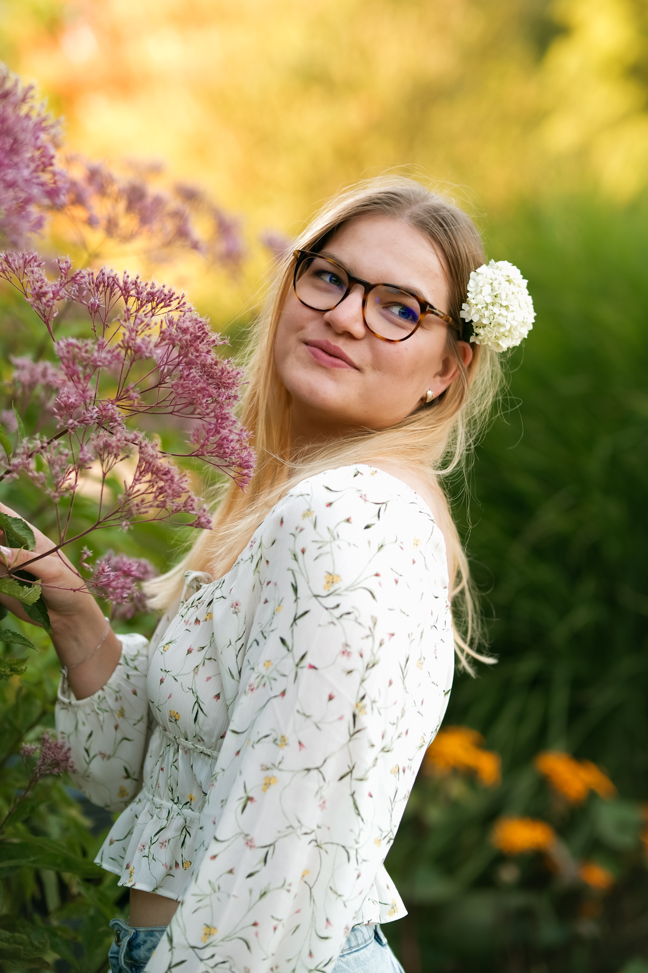 Frau mit Brille zwischen Blüten